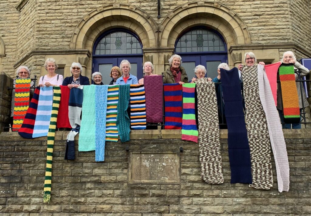 Members of the Thursday Friends group at Uppermill Methodist Church displaying the first batch of scarves collected by the church