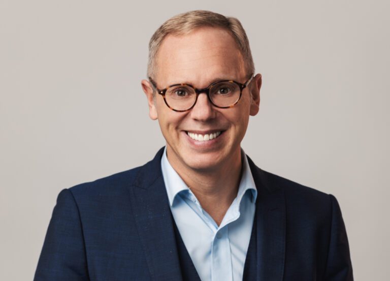 Rob Rinder, blonde-haired man smiling in blue suit